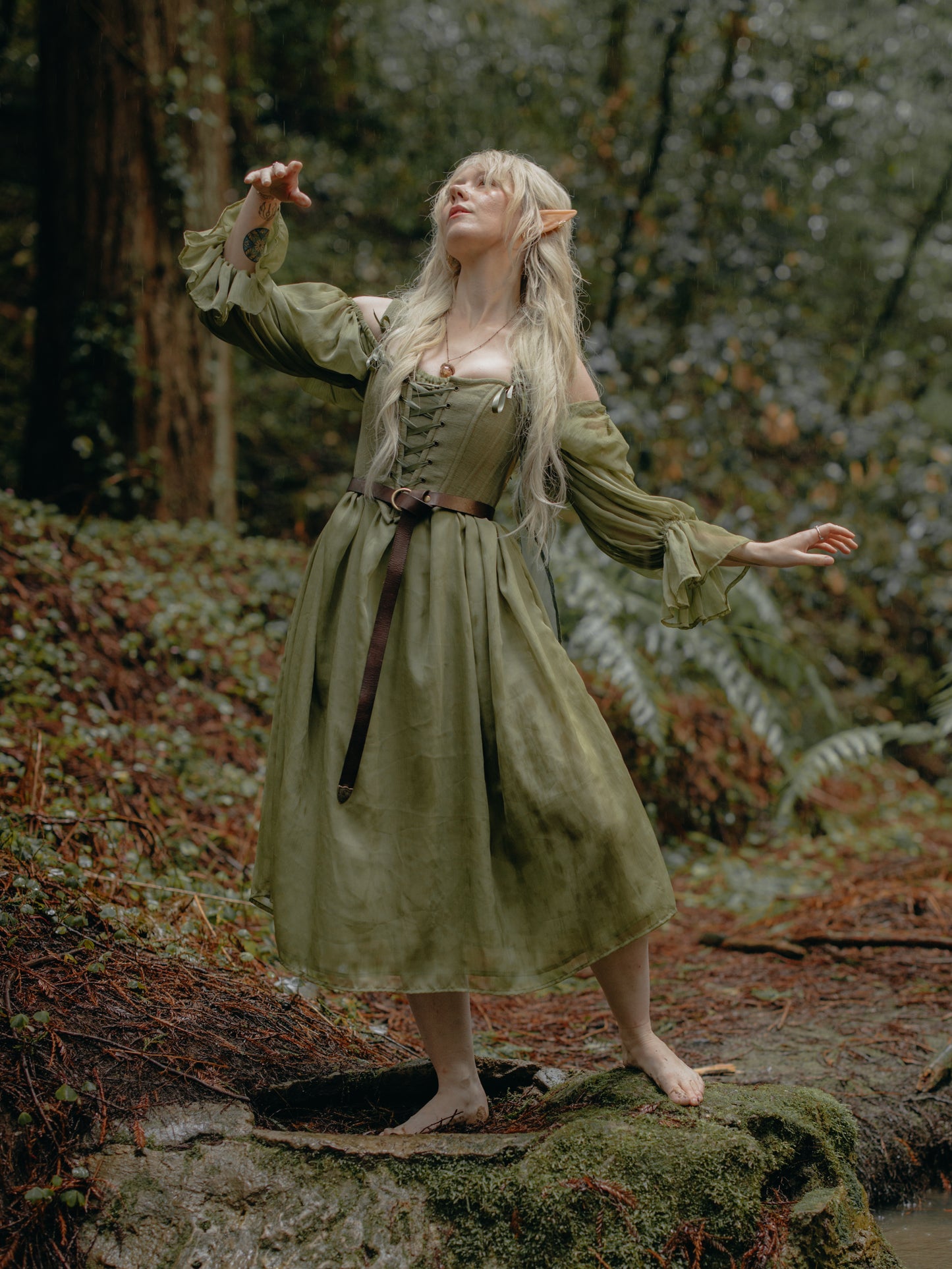 Woman in a forest wearing a flowing dress and Sage Cotton Corset with lace-up front and earthy green tone