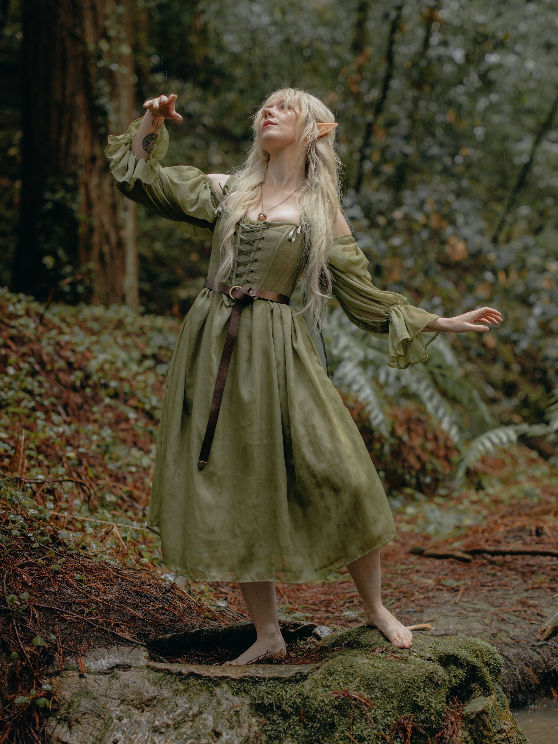 Woman in a forest wearing a flowing dress and Sage Cotton Corset with lace-up front and earthy green tone