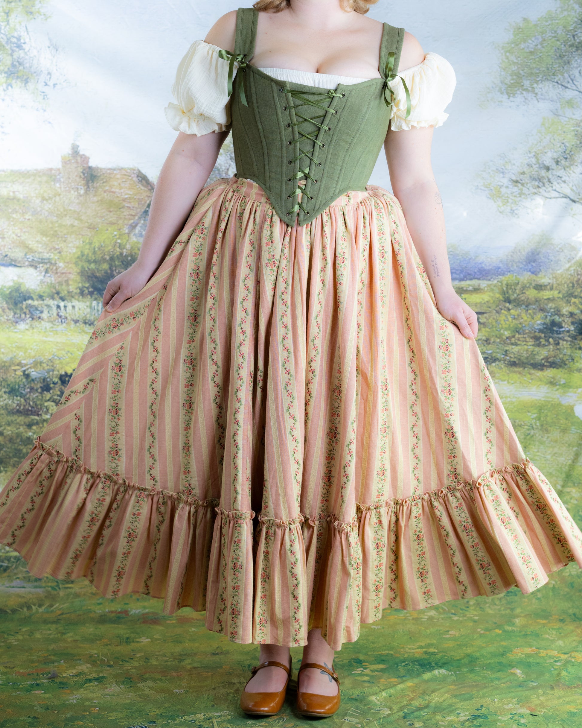 Woman wearing Rococo Pink Ruffle Skirt with floral stripes and ruffled hem, styled in vintage-inspired countryside setting