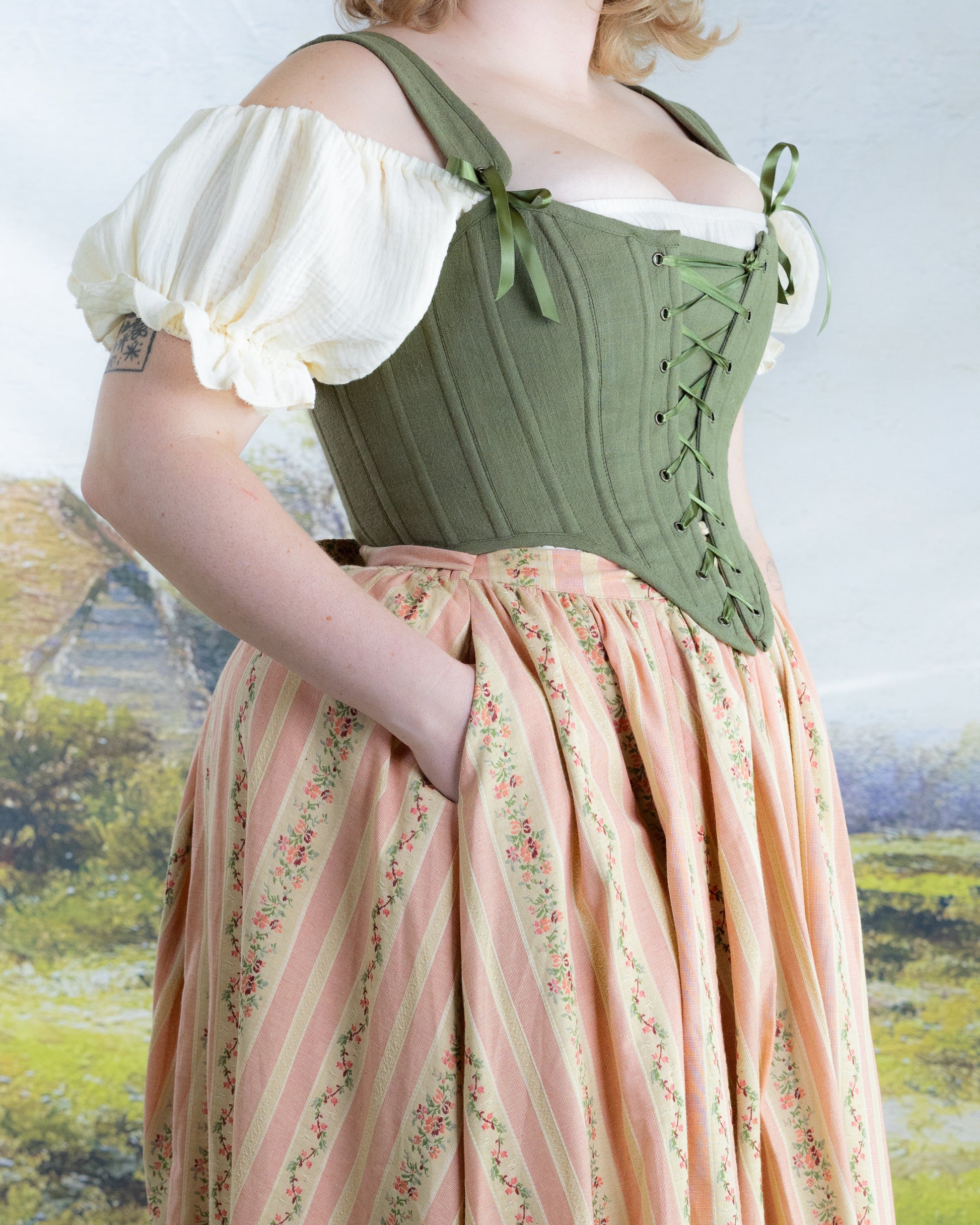 Woman wearing Rococo Pink Ruffle Skirt with floral stripes and a green corset top against soft scenic background