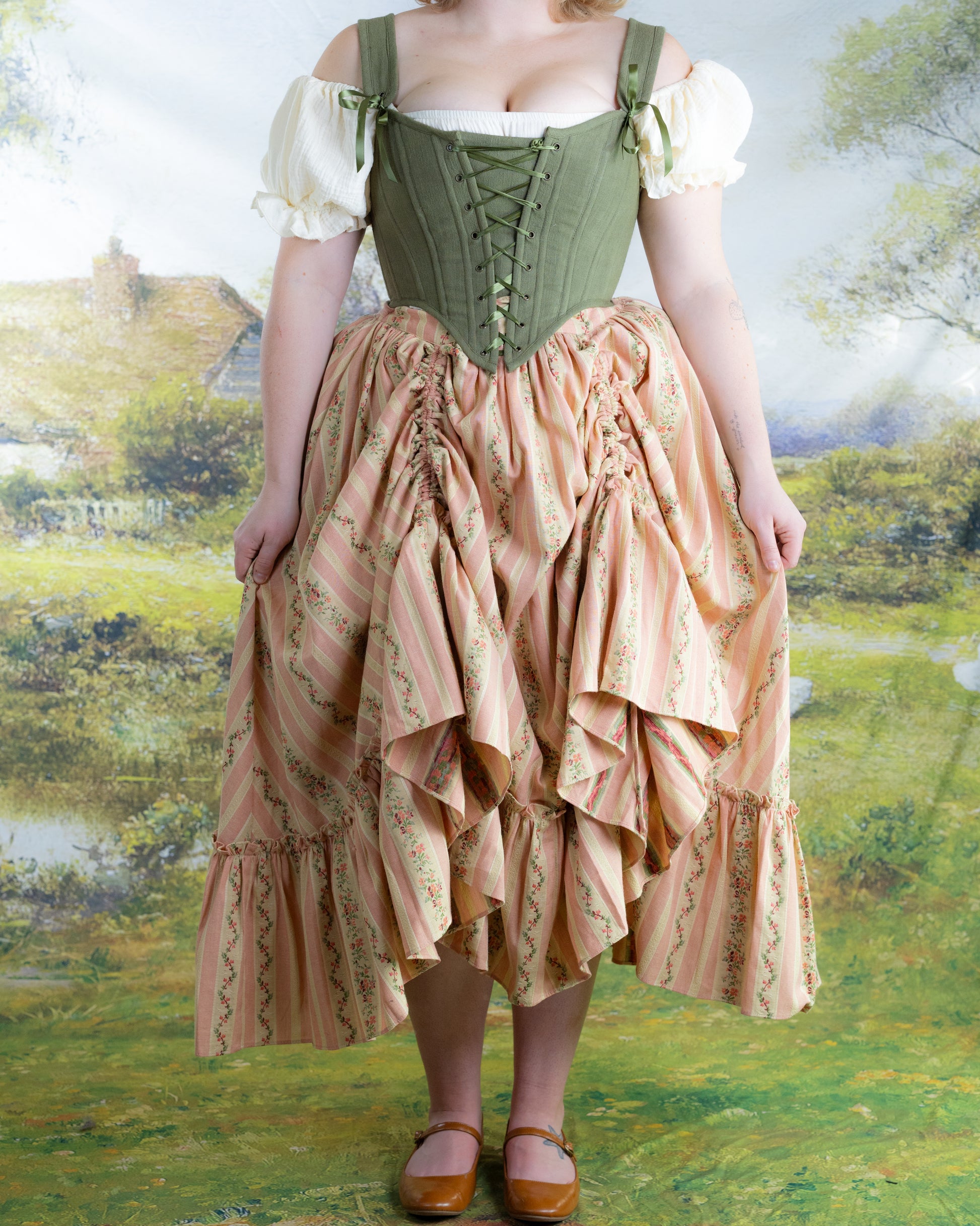 Woman wearing Rococo Pink Ruffle Skirt styled with a green corset top in an outdoor garden setting