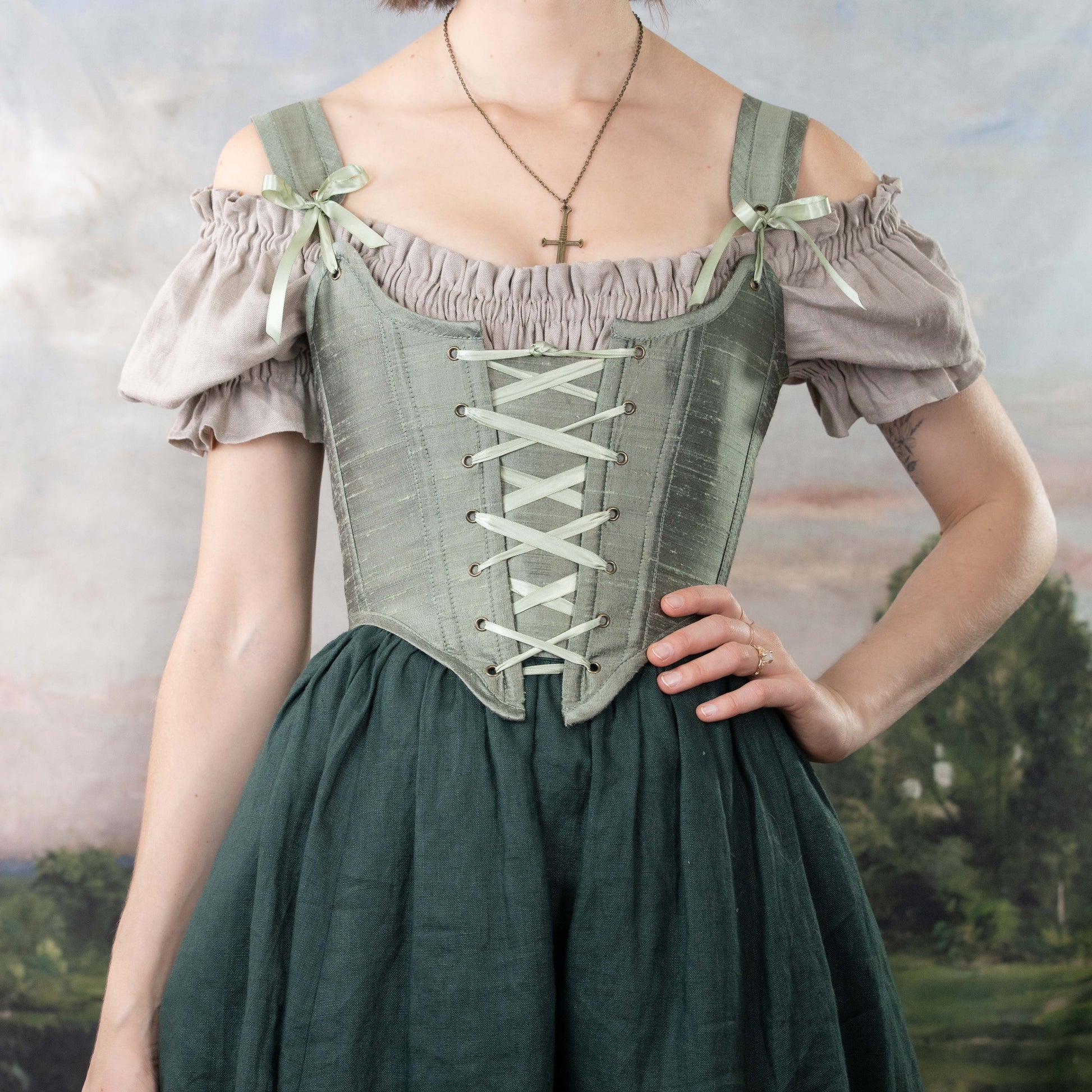 Woman wearing a Handmade Sage Green Silk Corset with lace-up front and vintage-inspired blouse and skirt.