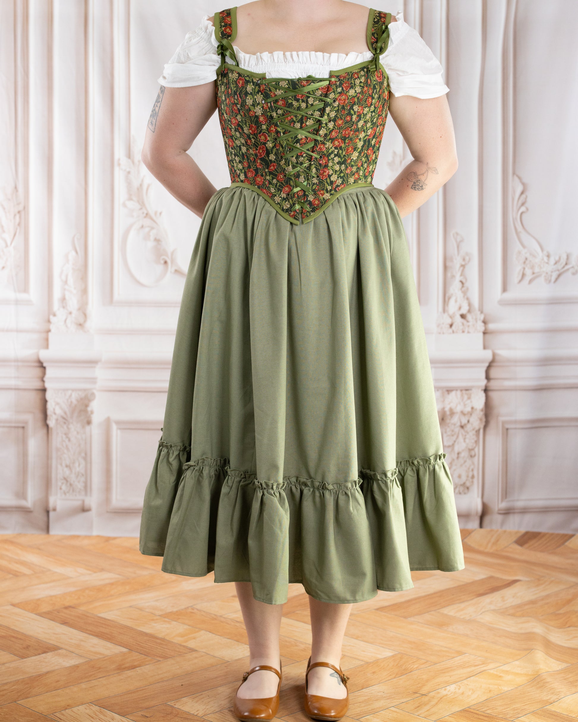 Woman wearing Sage Linen Ruffle Skirt with gathered ruffle hem standing on wooden floor in ornate room