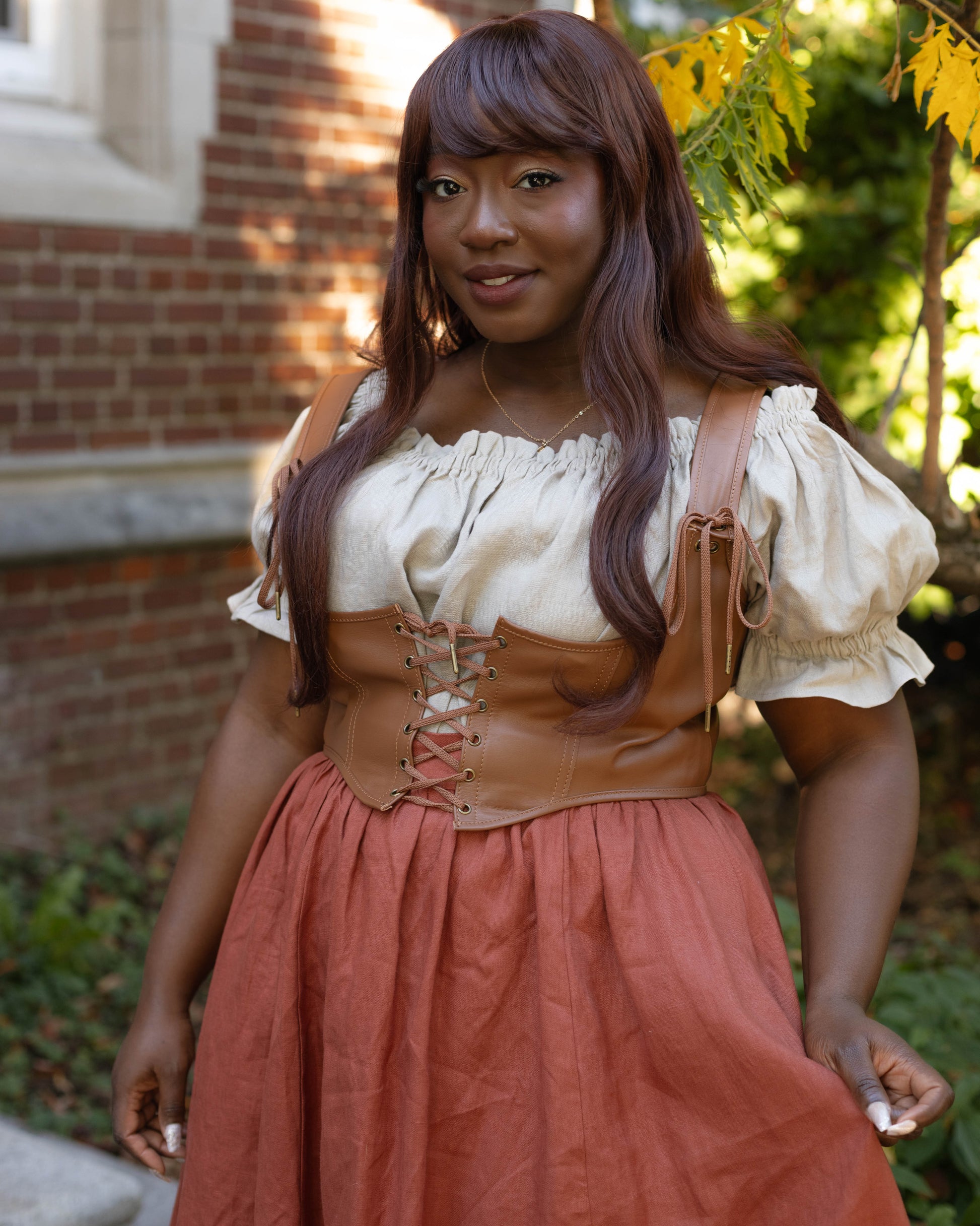 Leather Underbust Corset Belt worn over a white blouse and rust-colored skirt in an outdoor setting.