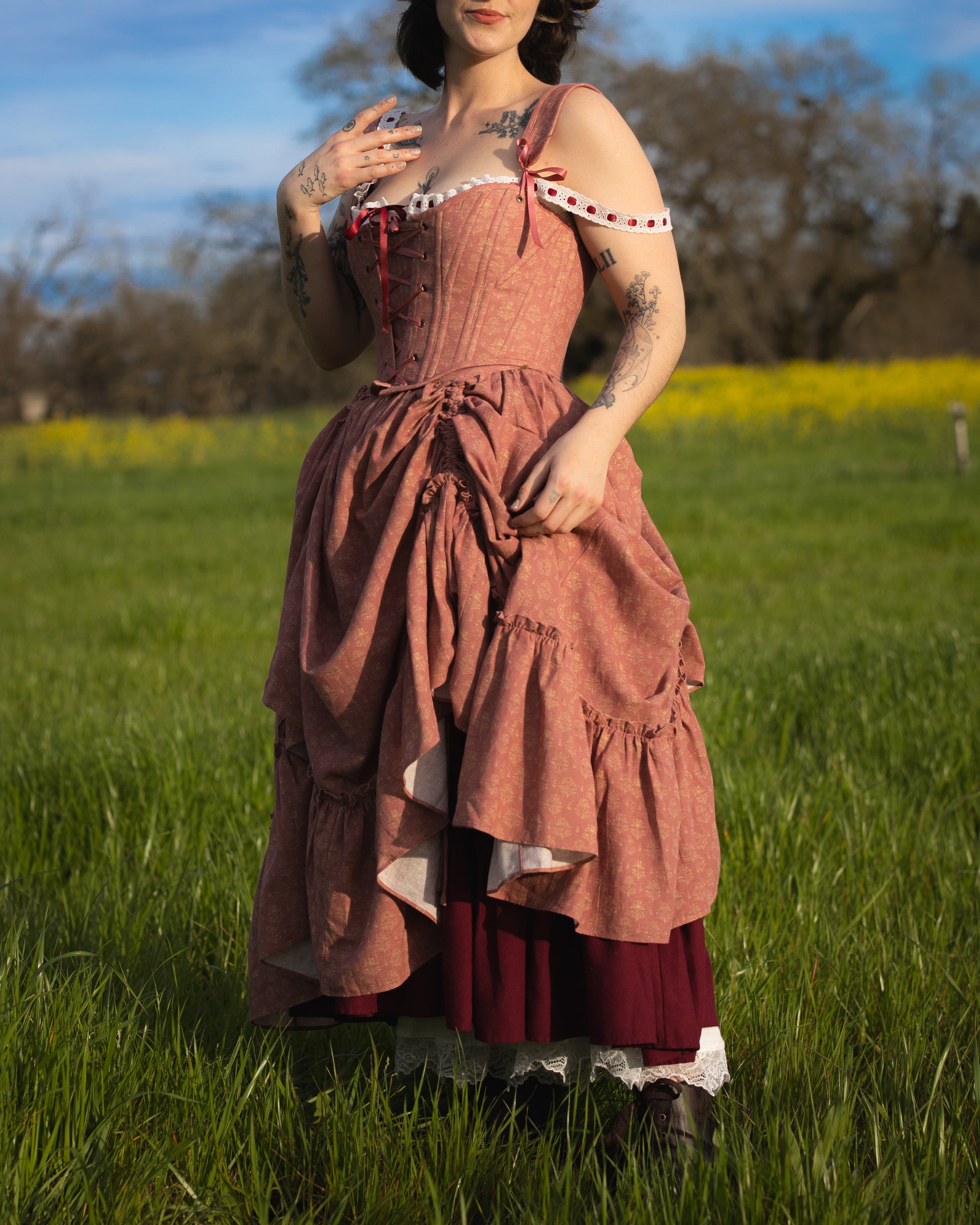 Woman wearing a layered vintage-style Strawberry Floral Ruffle Skirt standing in a grassy field with trees in the background