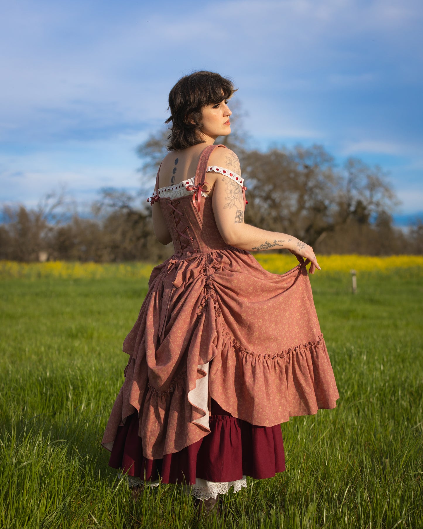 Woman standing in a field wearing a Strawberry Floral Ruffle Skirt with layered, ruffled design and floral print.