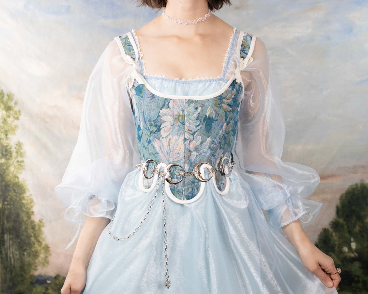 Woman wearing a delicate dress with sheer sleeves and a Handmade Teal Floral Tapestry 18th Century Stays corset belt accessory