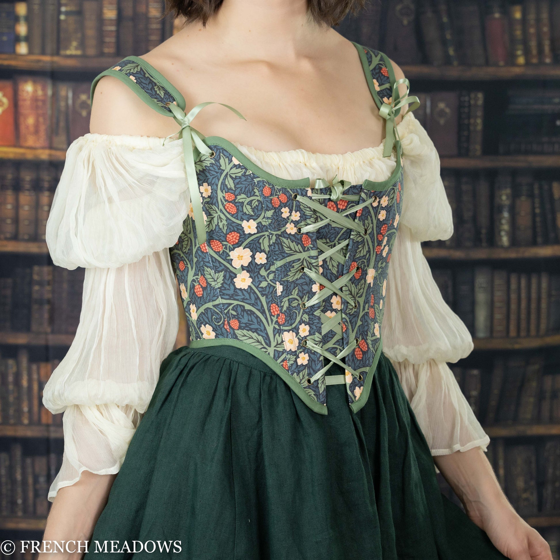 model wearing a green floral corset over a dark green linen skirt