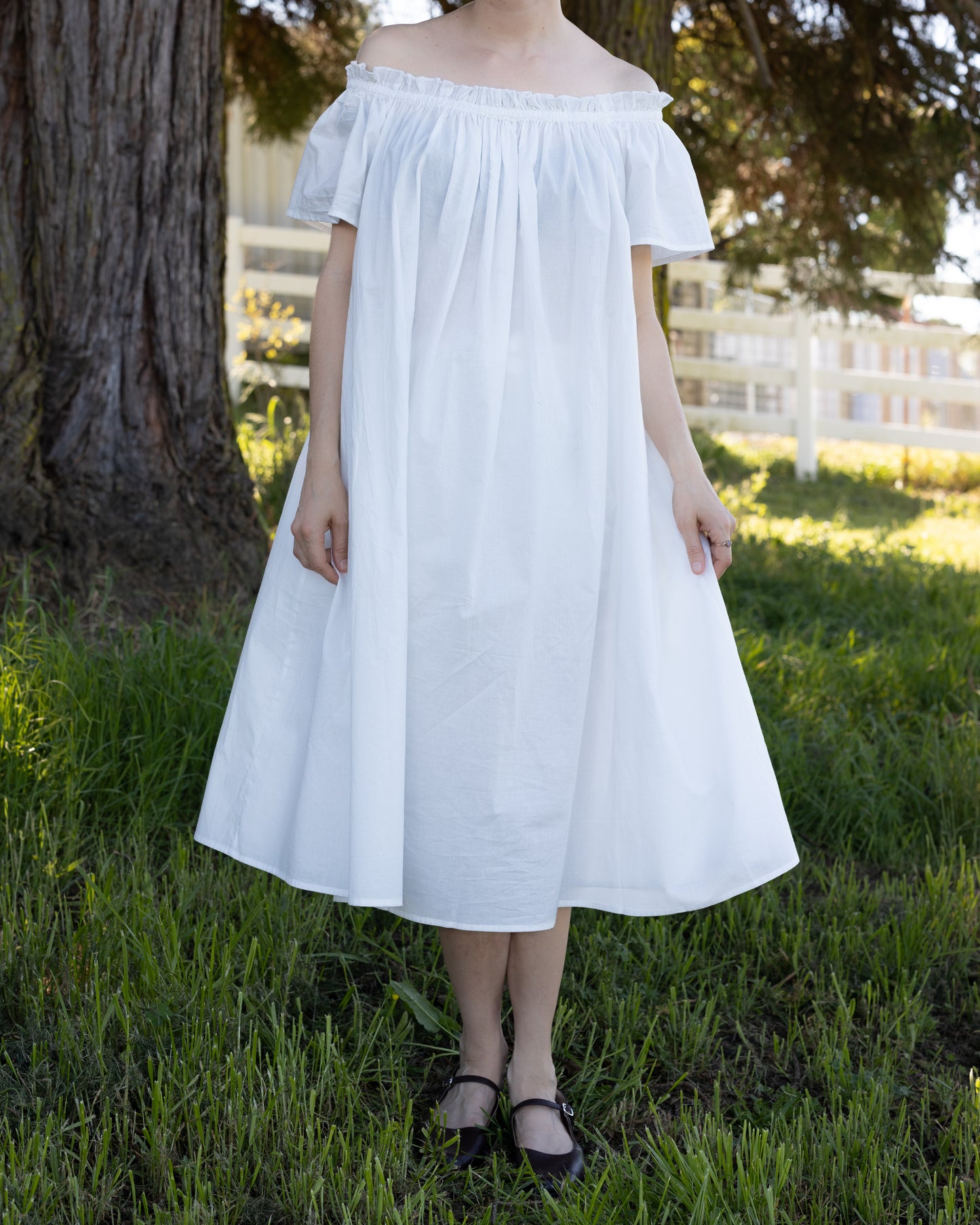 Woman outdoors wearing white Cotton Flutter Sleeve Chemise with elastic neckline in soft natural light for cottagecore look