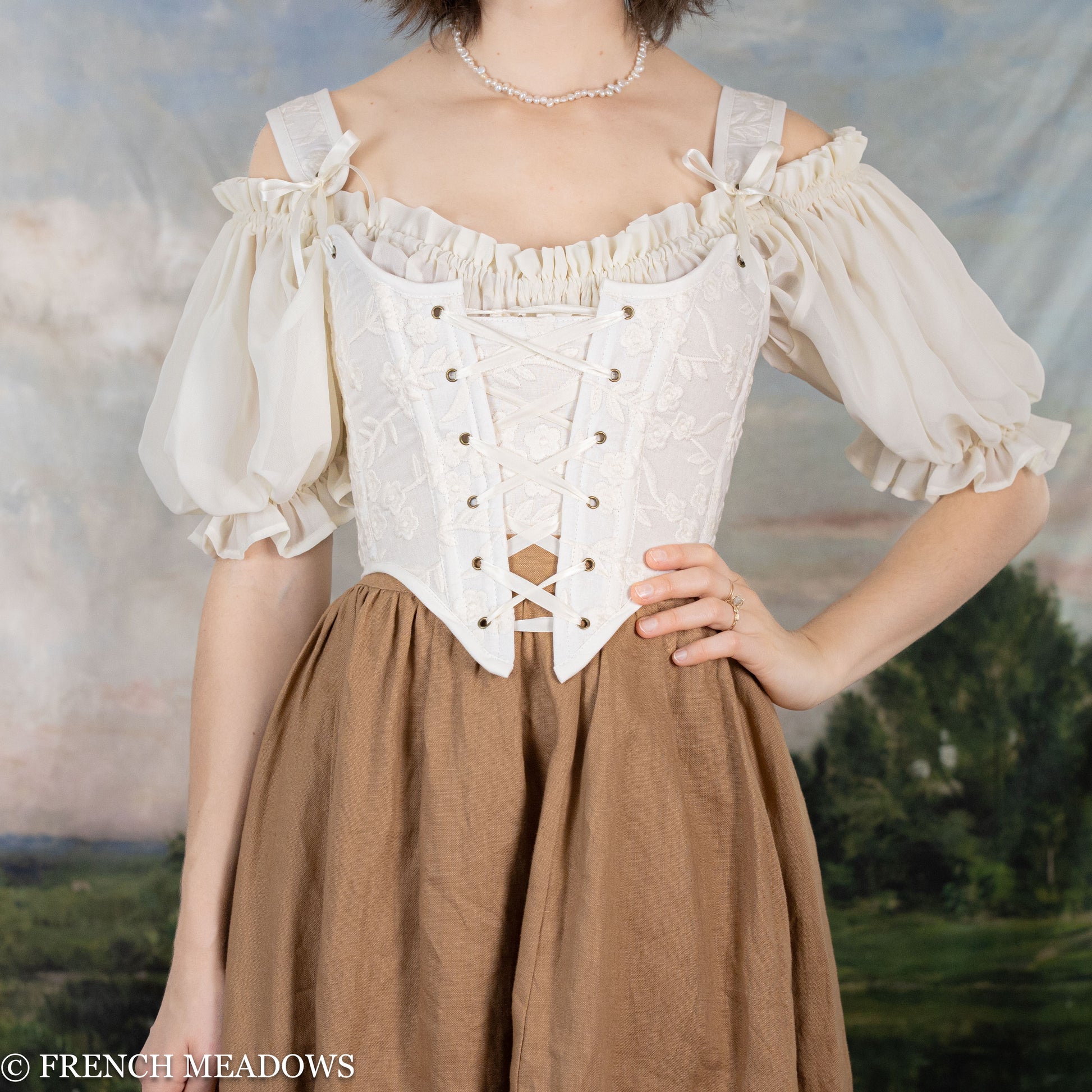 model wearing renaissance faire costume with a white corset dress and a linen skirt